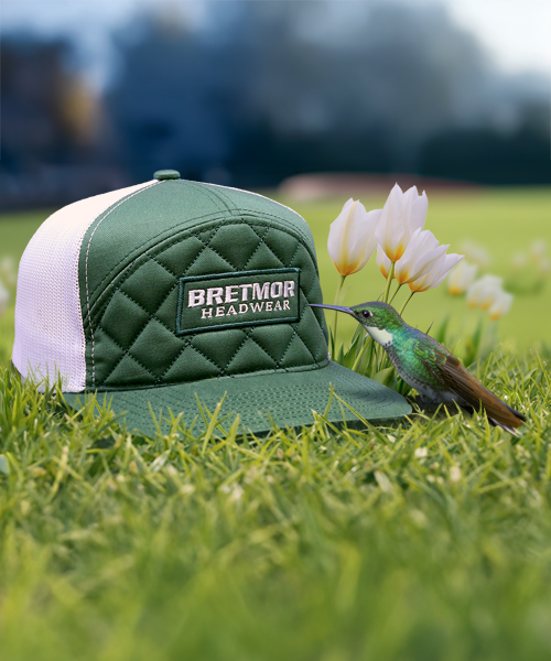 Background image of a cap with a leather patch on a post with hummingbirds hovering around it